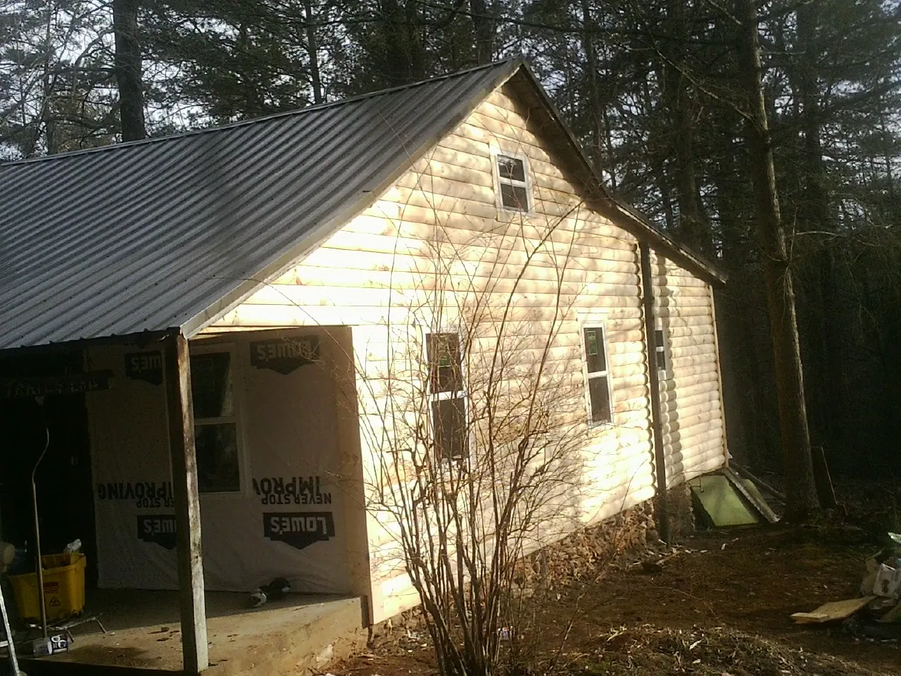 Log siding gable end under a dark metal roof edge in Brick