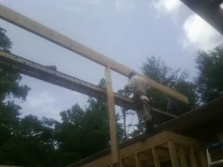 Carpenter setting a ridge beam over a new addition frame — Ice Dam Removal by Roofing Brothers in Brick